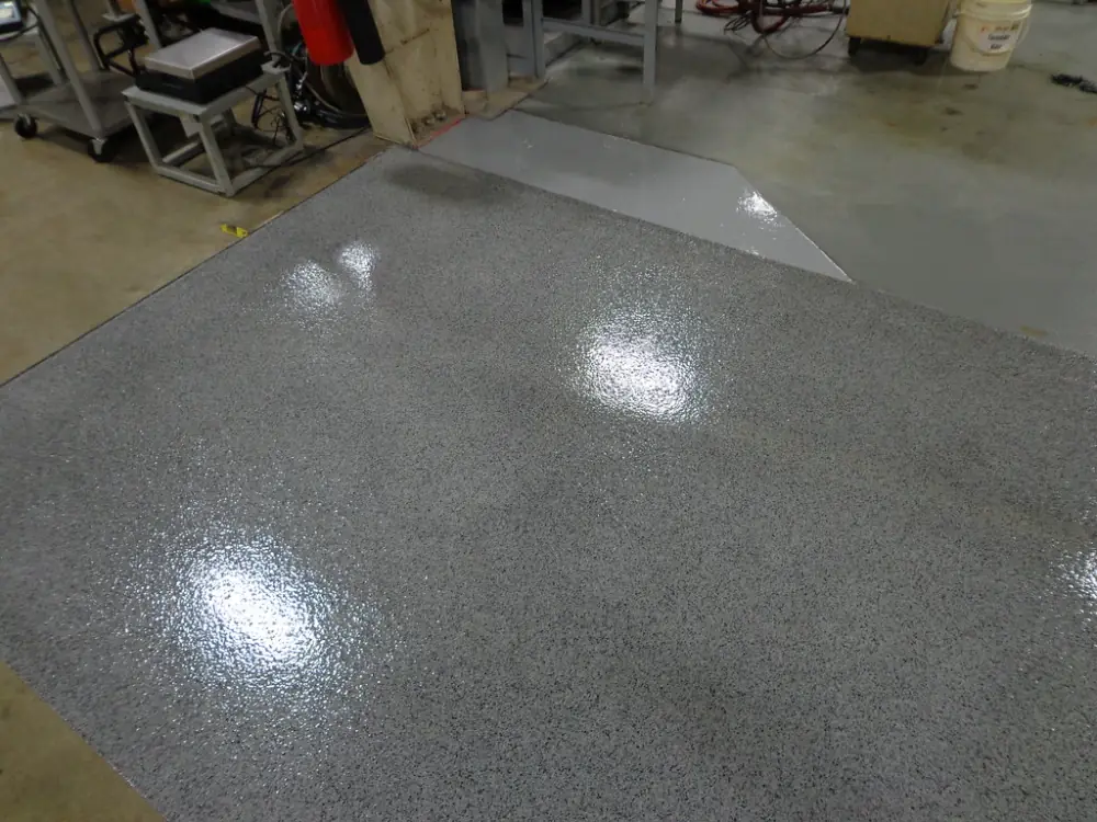 A shop floor with a glossy gray flake coating beside workbenches.