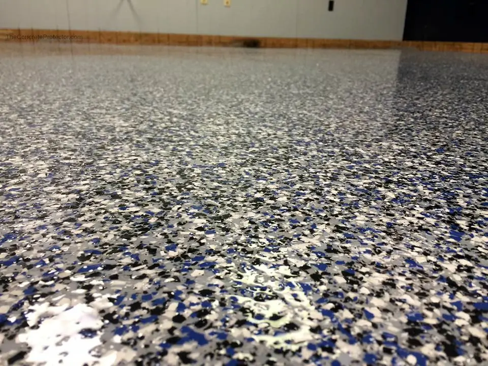 Close-up of a flake floor with gray, white, black and blue chips.