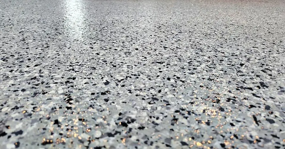 Low-angle close-up of a glossy gray, black and white flake floor.