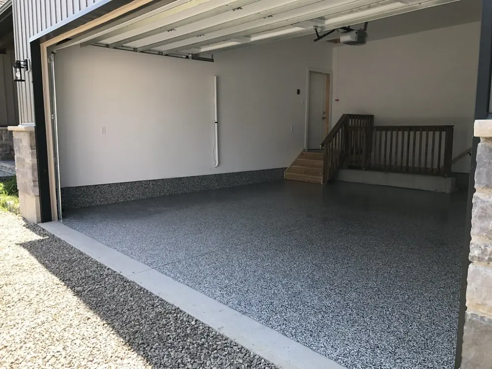 A two-car garage with a gray full-broadcast flake floor, seen through the open door.