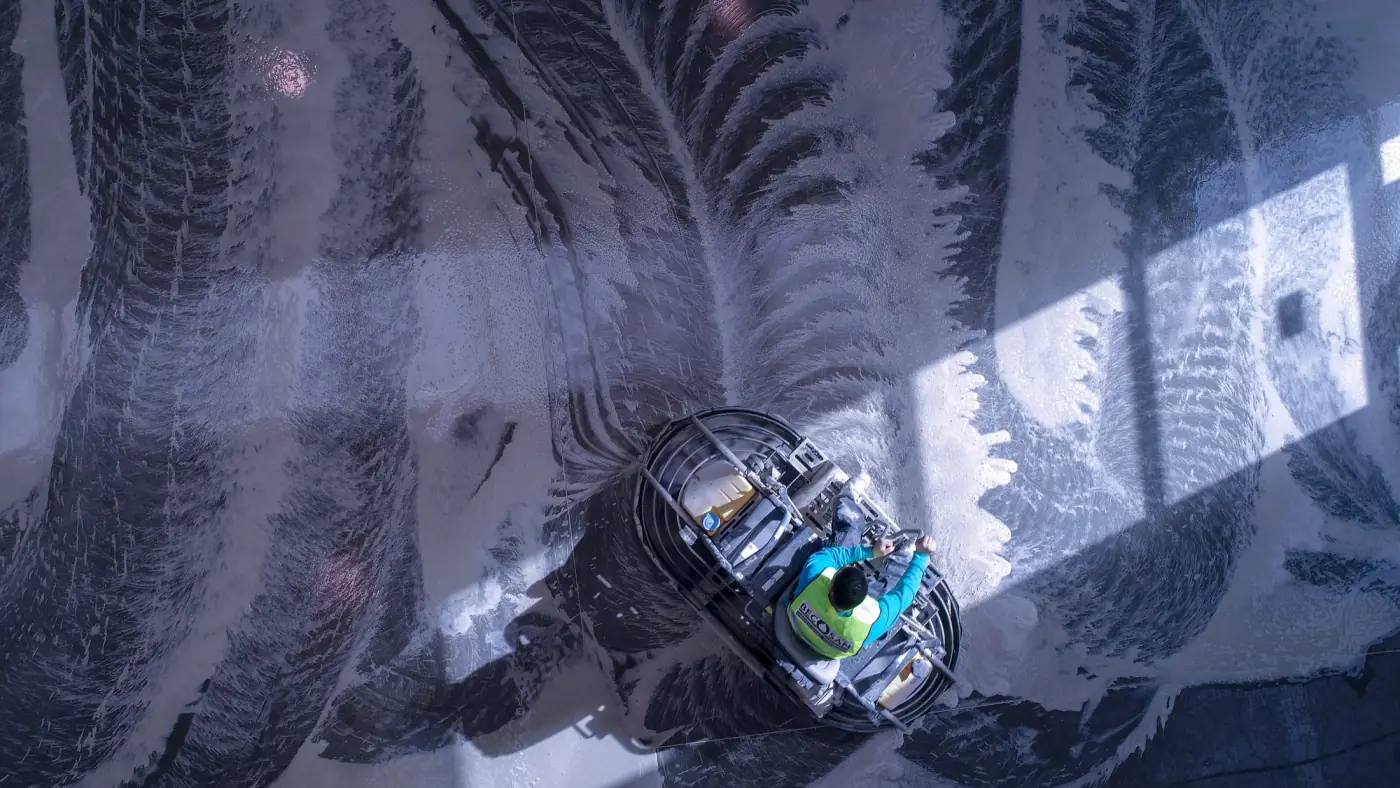Overhead view of a ride-on diamond grinder working an indoor concrete floor.