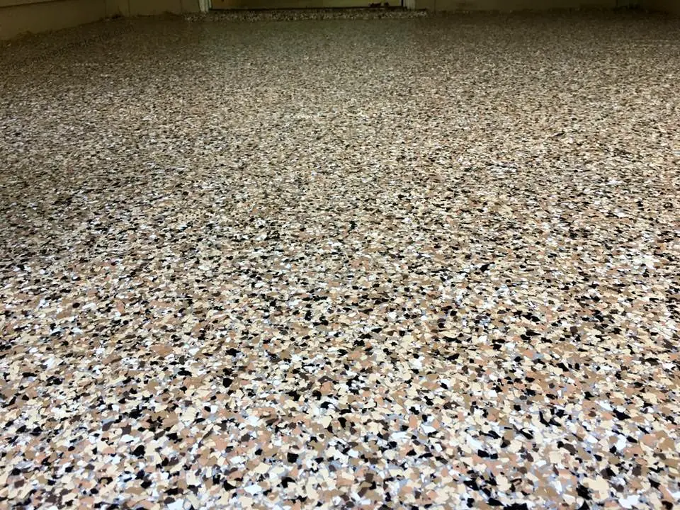 Close-up of a tan, brown, black and white flake coating on a porch.